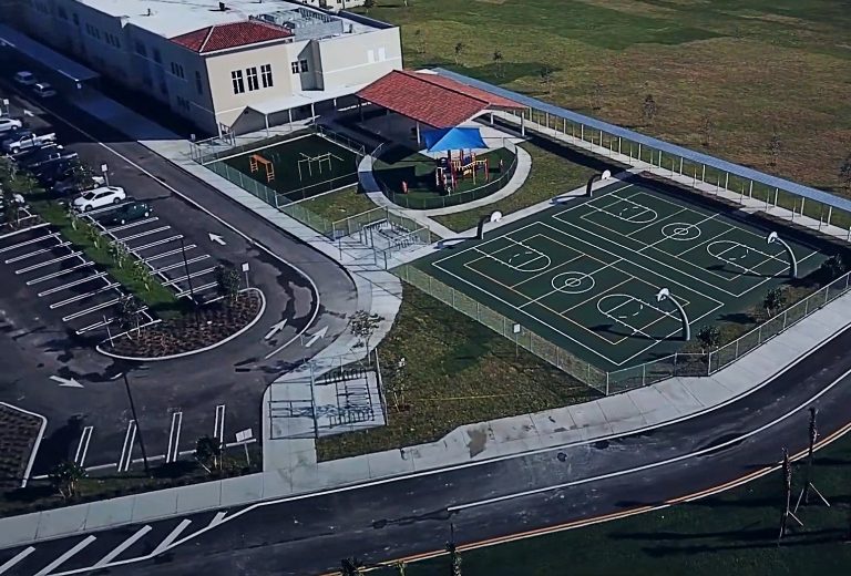 Aerial view of a basketball court, a parking lot, and a building